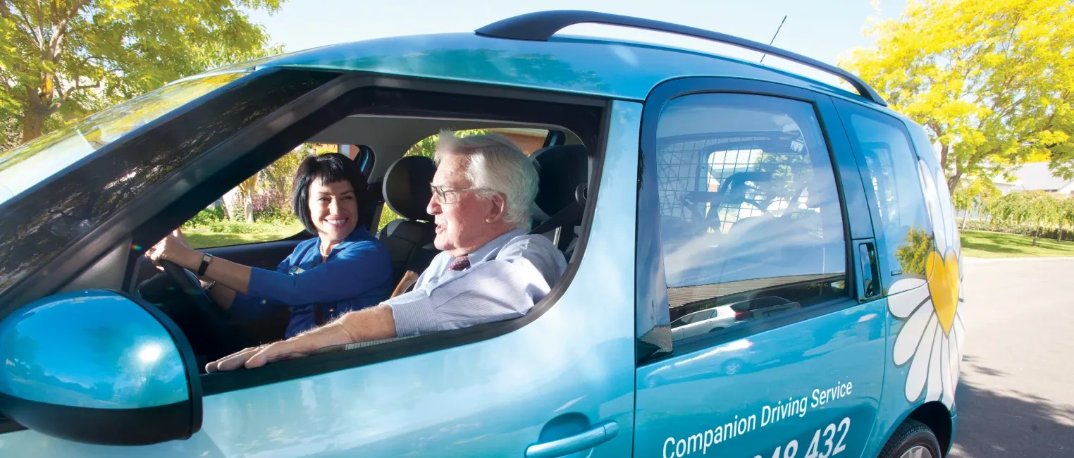 Driving Miss Daisy driver and passenger seated in a branded companion driving vehicle