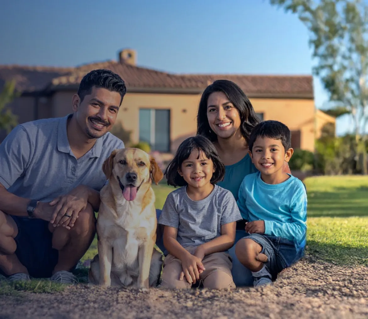 Family of four sitting on a lawn outside a house